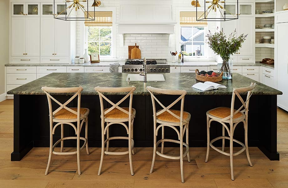 Alt: Large kitchen with white cabinets and backsplash, midcentury chandeliers and island with Jatoba Green 180fx Laminate countertop with chairs