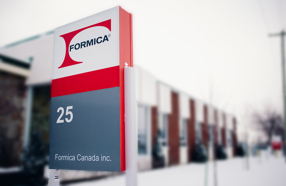 Close-up of the Formica Canada office sign featuring the company logo with building in background