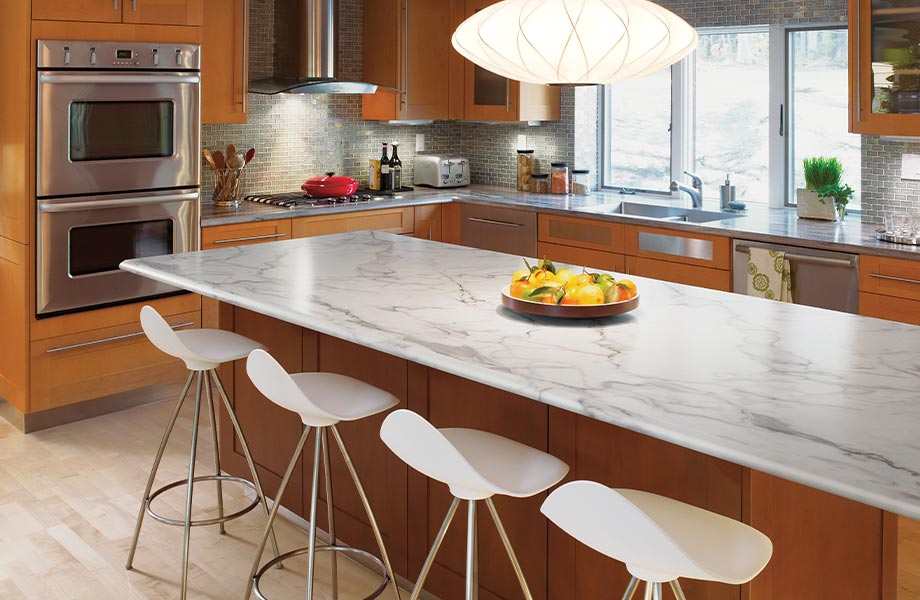 A modern home kitchen with an island in the foreground, featuring 3460 Calacatta Marble 180fx Laminate by Formica Group