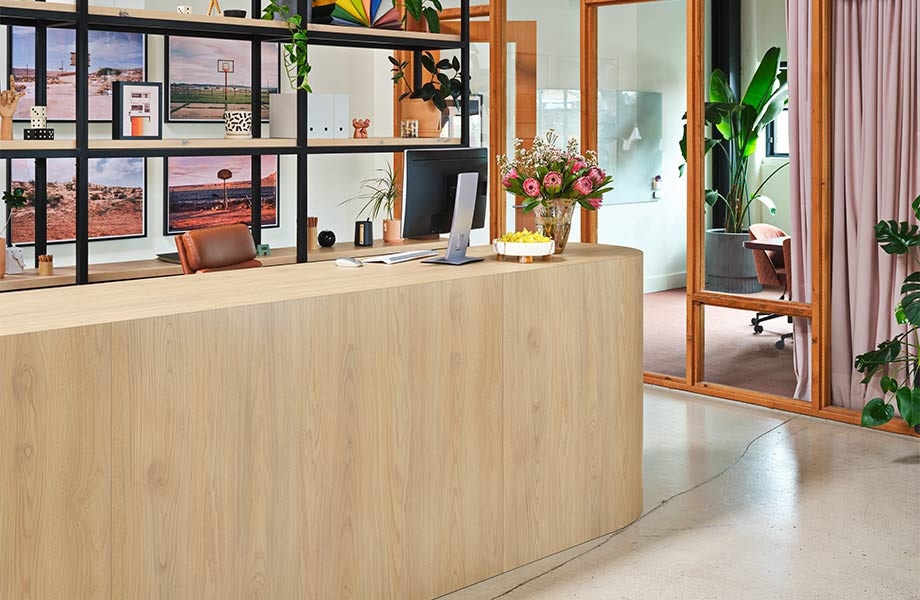 Reception area with display shelving, glass-paned offices and large desk in Natural White Oak Formica Laminate