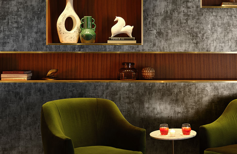 Elegant sitting area with green chairs, vases and books against Metallic Black Homapal metal Laminate accent wall