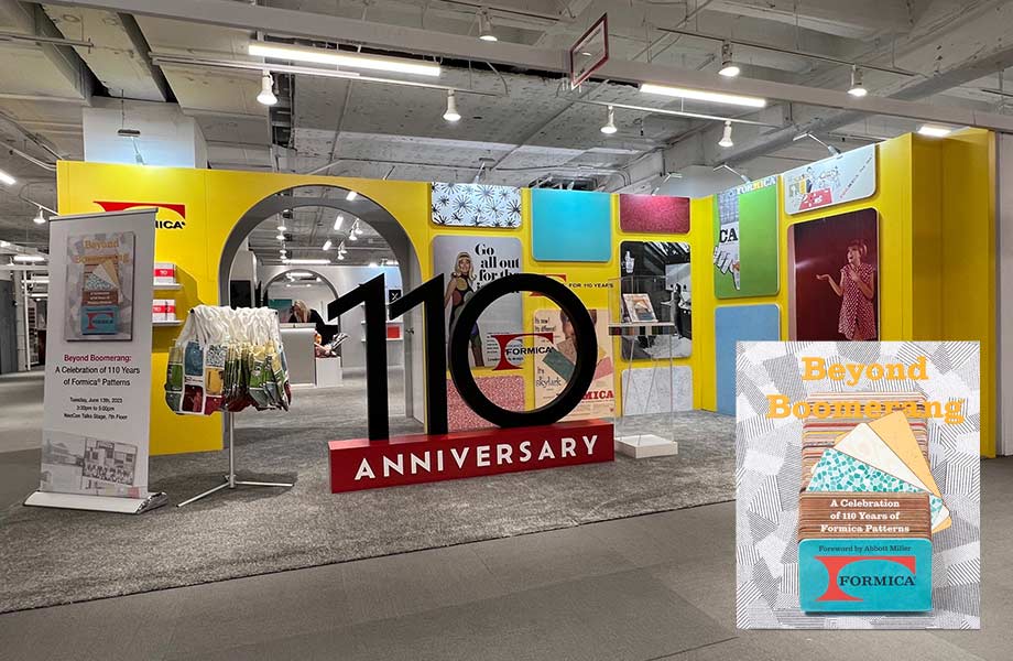 Une grande enseigne 3D « 110e anniversaire » noir et rouge au sol entouré de publicités historiques de la marque Formica et de couleurs à l’intérieur d’un kiosque avec une image dans le coin du livre « Beyond Boomerang » 